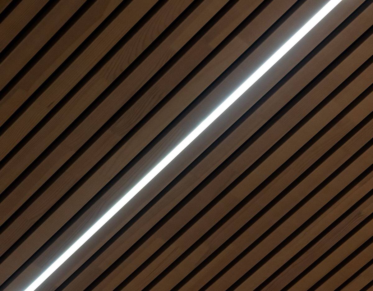 Gros plan d'une solution pour plafonds suspendus, profilé en aluminium et bande LED à température de couleur réglable dans la rainure de la dalle de plafond